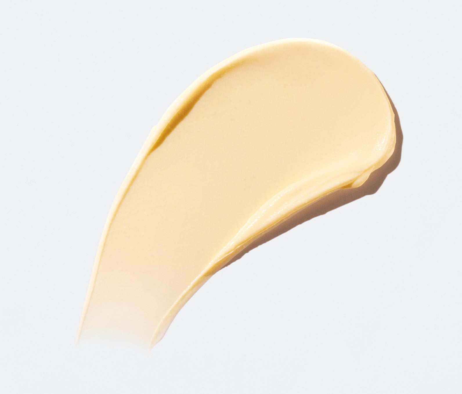 Swipe of Ursa Major Golden Hour Recovery Cream on a light-gray background.  Golden Hour Recovery Cream is light-yellow in color.