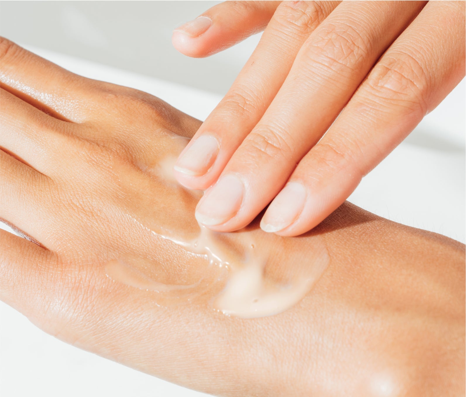 Hand rubbing in Ursa Major Fortifying Gel Moisturizer onto the back of the other hand.